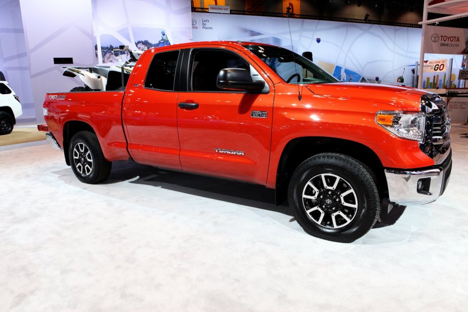 Orange Toyota Tundra pickup truck parked on stage at the Chicago auto show with an ATV in its bed.