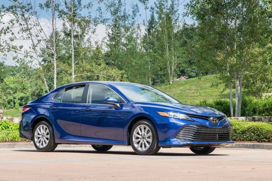 A blue used Toyota Camry shows off its side profile in the with black accents.