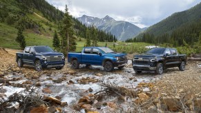 Three 2023 Chevrolet Silverado trucks parked in front of a mountain.