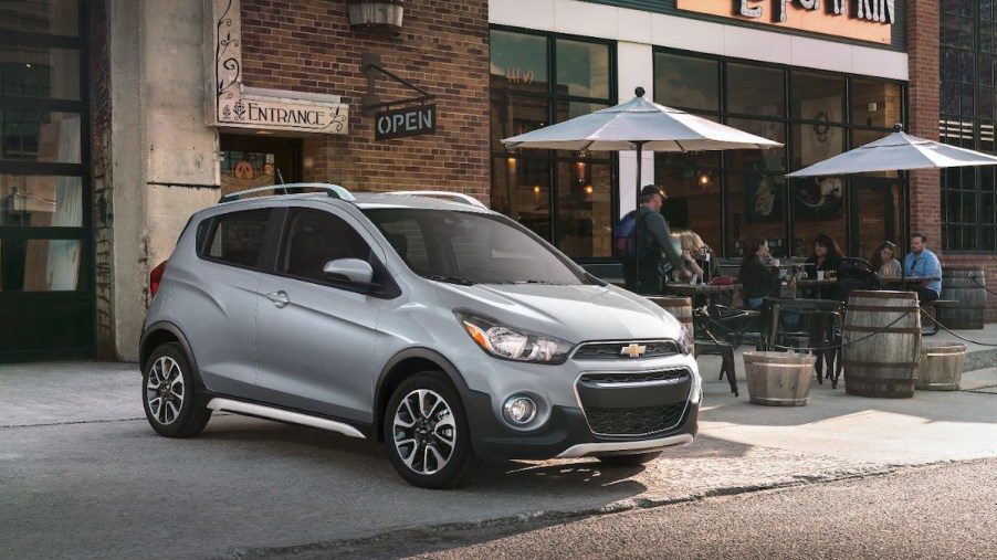 A silver 201 Chevrolet Spark parked out doors, which is the Chevrolet with the lowest insurance cost.