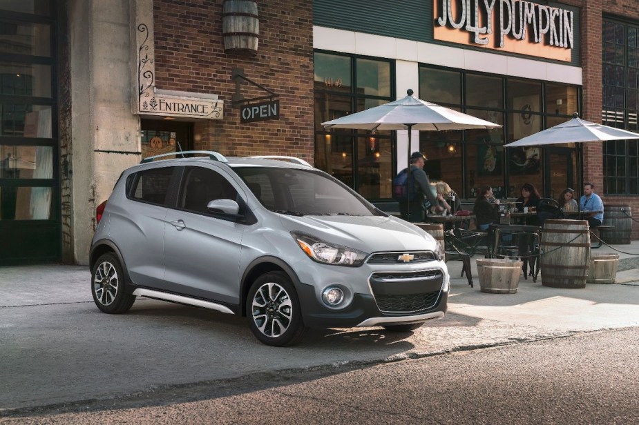 A silver 201 Chevrolet Spark parked out doors, which is the Chevrolet with the lowest insurance cost. 
