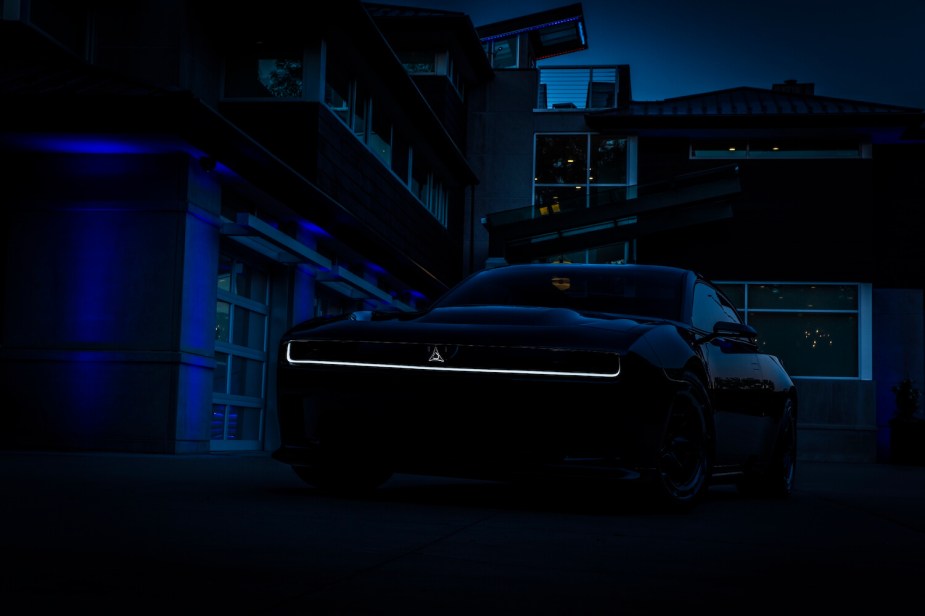 Advertising photo of the illuminated grille of the electric Dodge Charger Daytona SRT Banshee, the car's silhouette visible against the night sky.