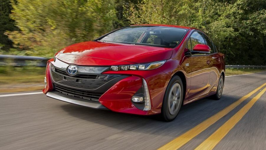 A 2022 Toyota Prius Prime PHEV blasts down a back road in bright red.