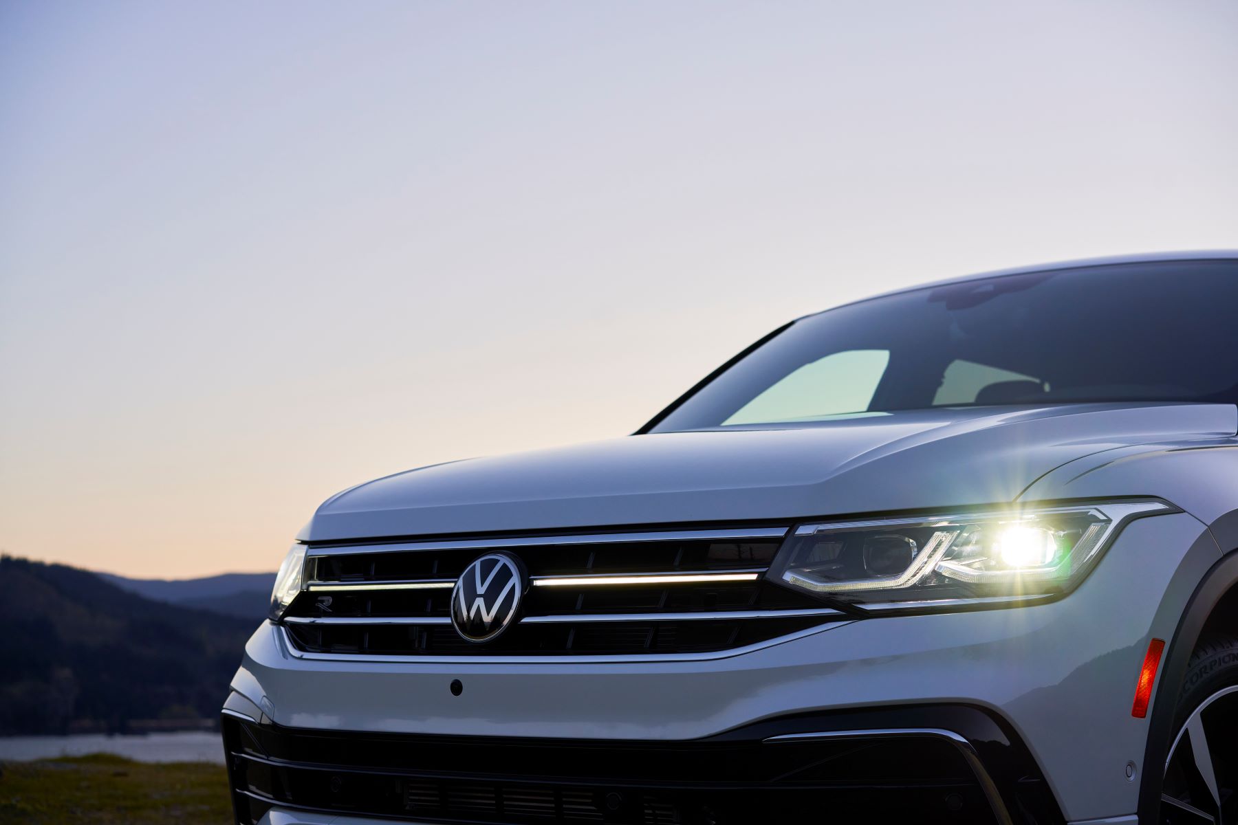 A closeup exterior shot of the grille and headlights of a white 2022 Volkswagen Tiguan SEL R-Line compact SUV model