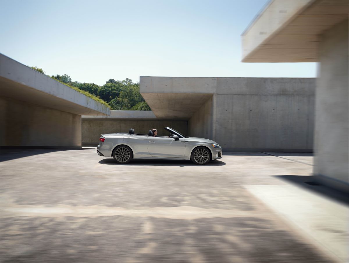A woman is driving a gray 2023 Audi A5 Cabriolet