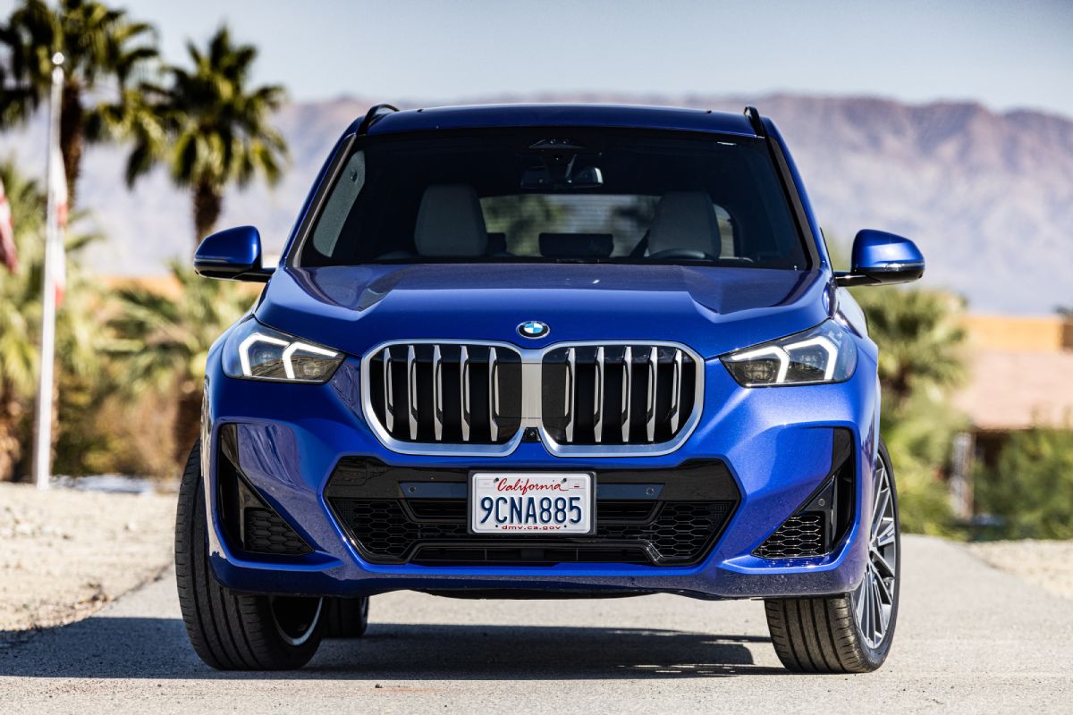 A blue 2023 BMW X1 driving down the road.