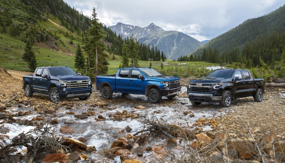 A lineup of different 2023 Chevy Silverados on a riverbed.