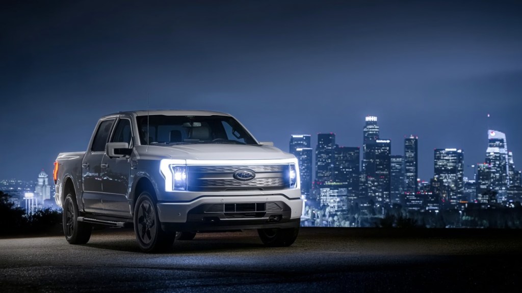 The 2023 Ford F-150 Lightning parked near a city at night 