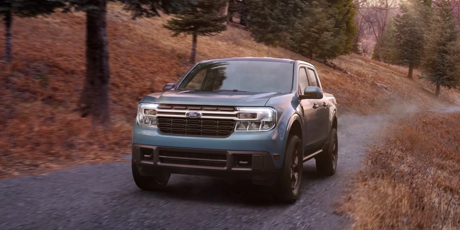 A blue 2023 Ford Maverick small pickup truck is driving off-road. 
