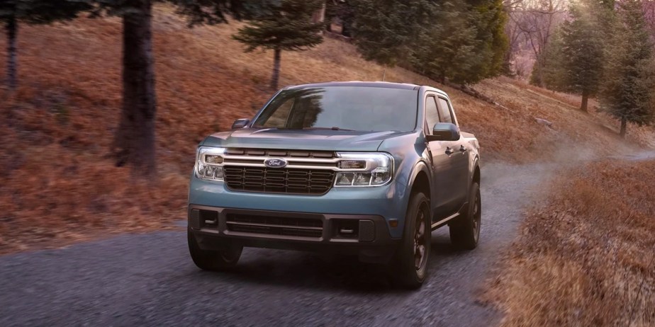 A blue 2023 Ford Maverick small pickup truck is driving off-road.