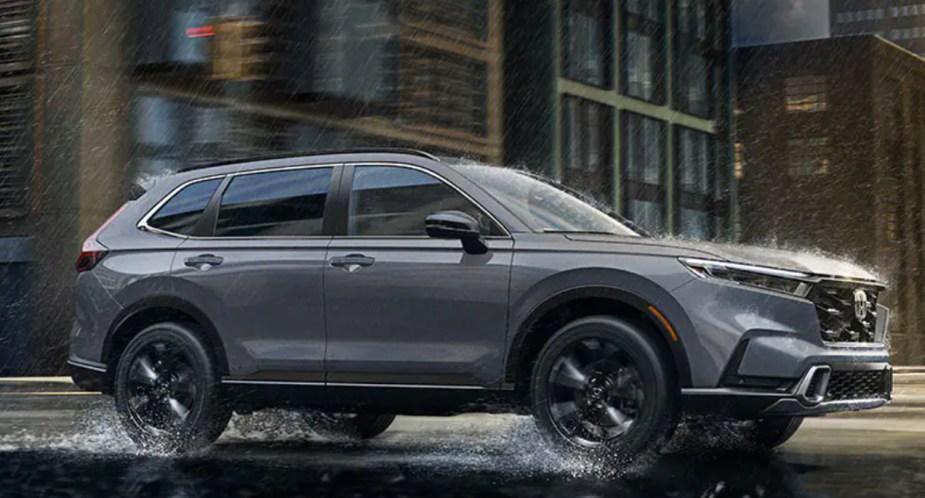 A gray 2023 Honda CR-V small SUV is driving on the road in the rain. 