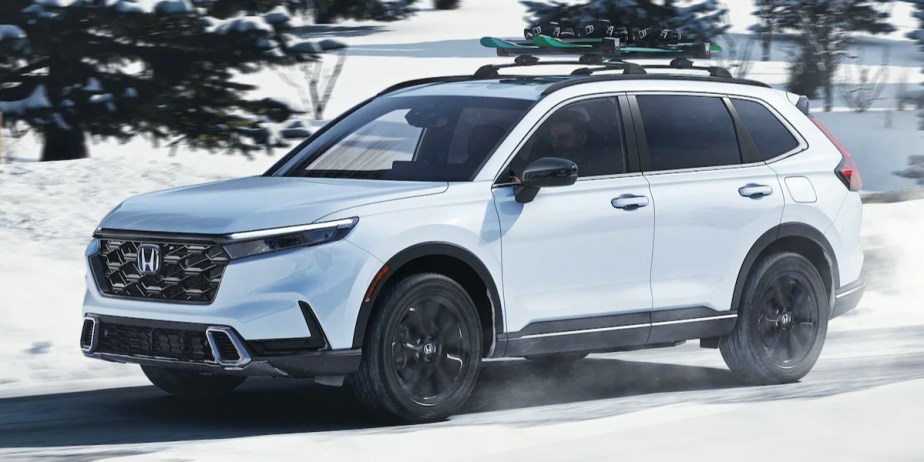 A white 2023 Honda CR-V small SUV is driving in a snowy area. 