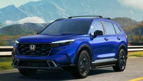 A blue 2023 Honda CR-V small SUV is driving on the road.