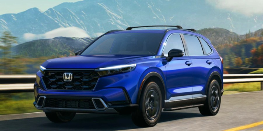 A blue 2023 Honda CR-V small SUV is driving on the road.