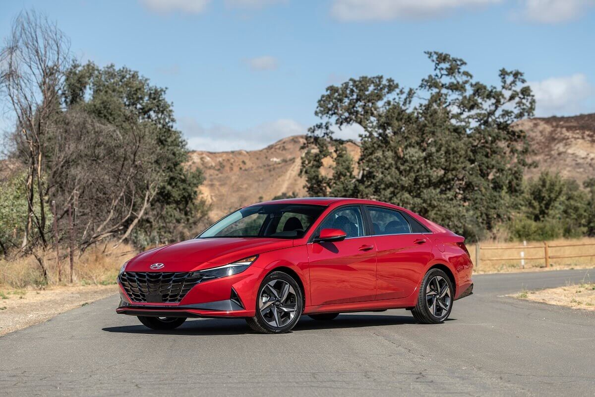 This red car showing off its side profile and sedan styling is a 2023 Hyundai Elantra Blue Hybrid.