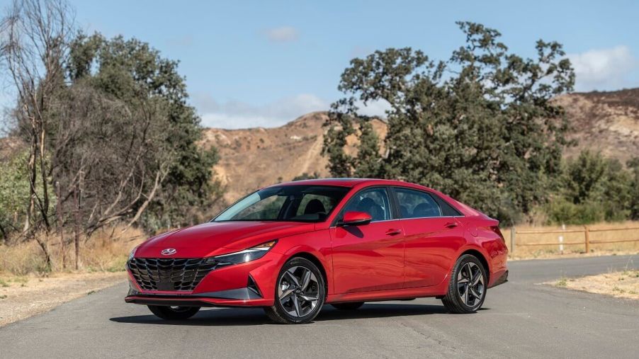 This red car showing off its side profile and sedan styling is a 2023 Hyundai Elantra Blue Hybrid.