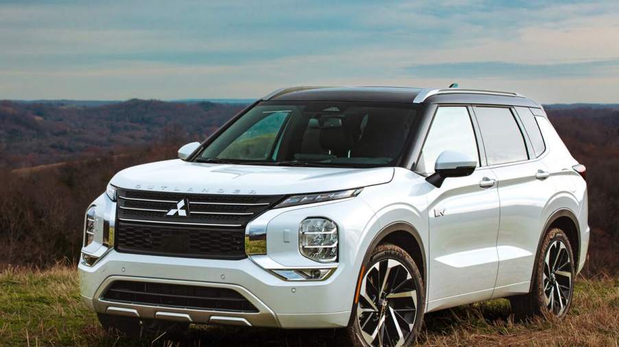 A white 2023 Mitsubishi Outlander parked outdoors in a grassy area.
