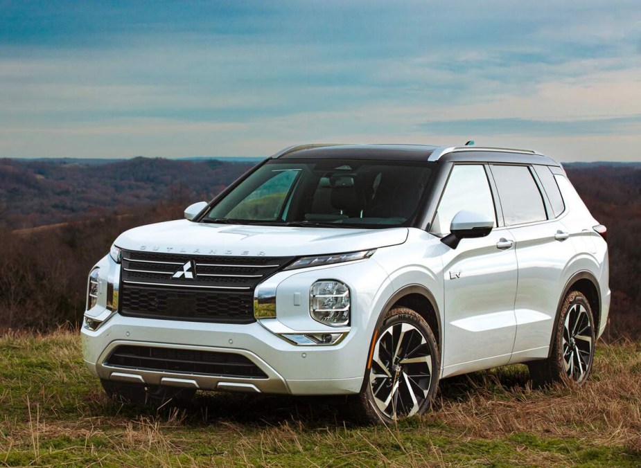 A white 2023 Mitsubishi Outlander parked outdoors in a grassy area. 