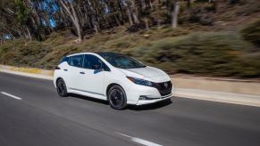 A white 2023 Nissan LEAF shows off its simple aesthetic as it cruises back roads.