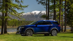 A blue 2023 Nissan Pathfinder parked in a wooded area.