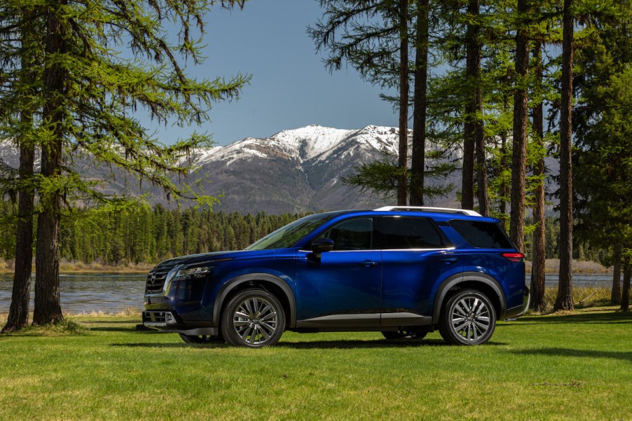 A blue 2023 Nissan Pathfinder parked in a wooded area.