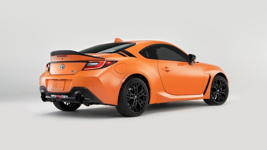 An orange 2023 Toyota GR86 coupe shows off its rear-end styling and spoiler.