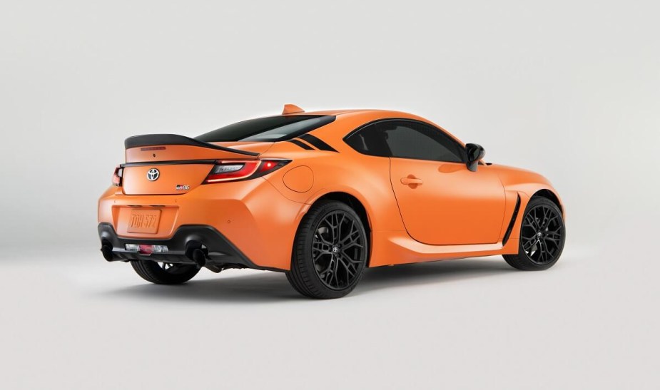 An orange 2023 Toyota GR86 coupe shows off its rear-end styling and spoiler.