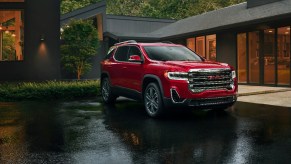 Red 2023 GMC Acadia midsize three-row SUV parked in the rain, experts recommend one trim.