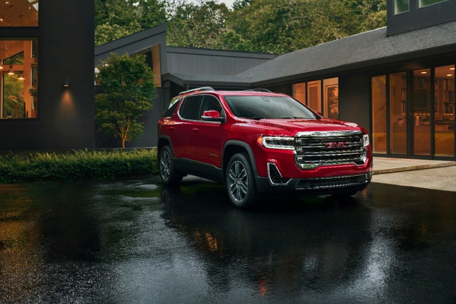 Red 2023 GMC Acadia midsize three-row SUV parked in the rain, experts recommend one trim.