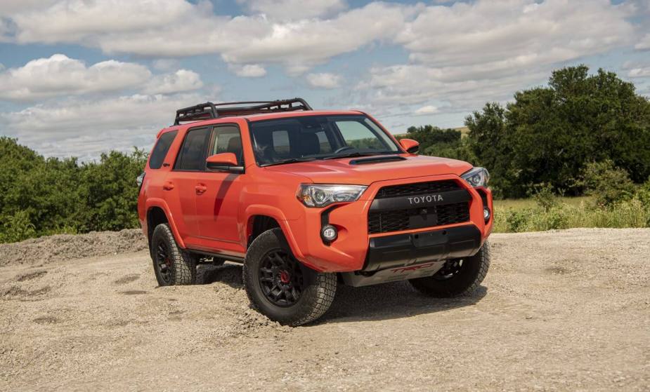 Bright orange 2023 Toyota 4Runner TRD Pro parked on a sandy trail, trees visible in the background.