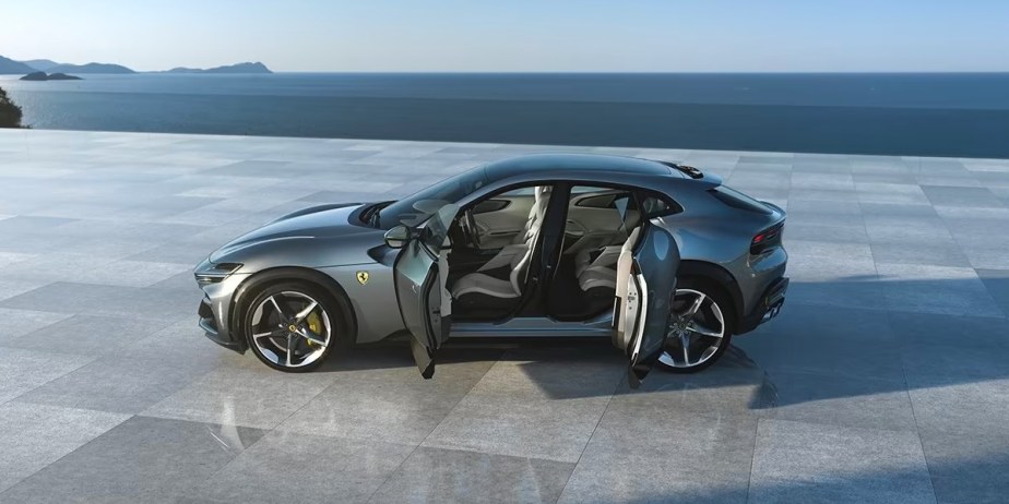 A gray 2024 Ferrari Purosangue luxury performance SUV is parked with doors open. 