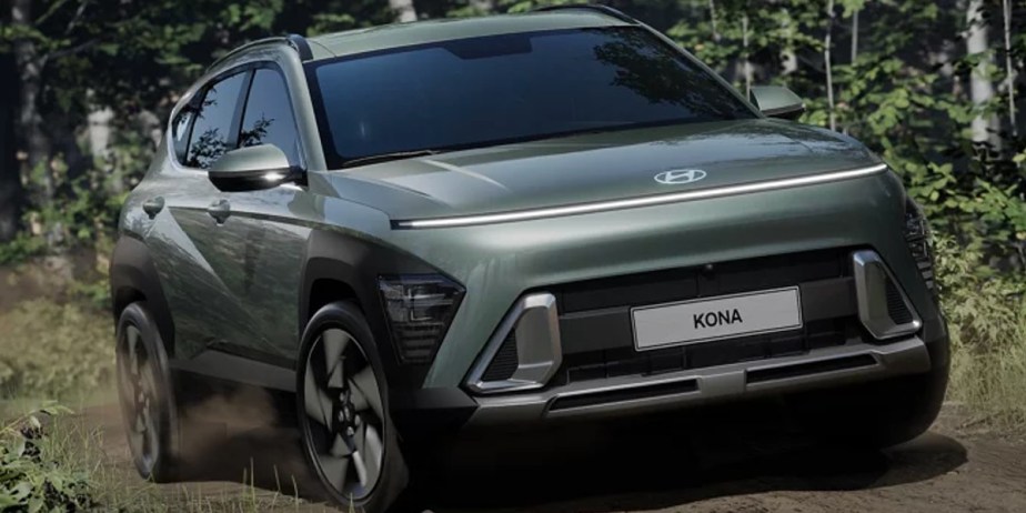 A green 2024 Hyundai Kona subcompact SUV is driving off-road. 