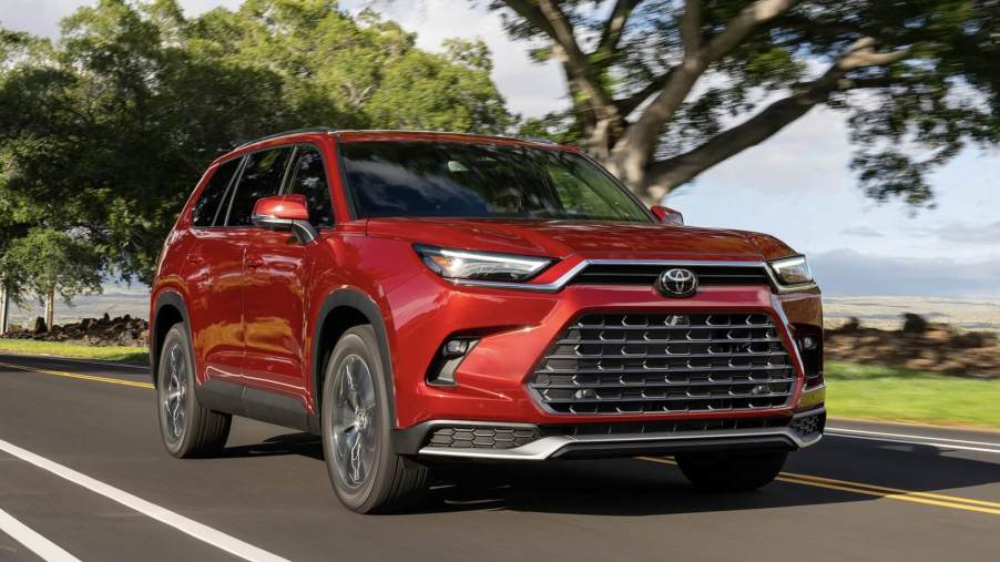 A red 2024 Toyota Grand Highlander driving down the road