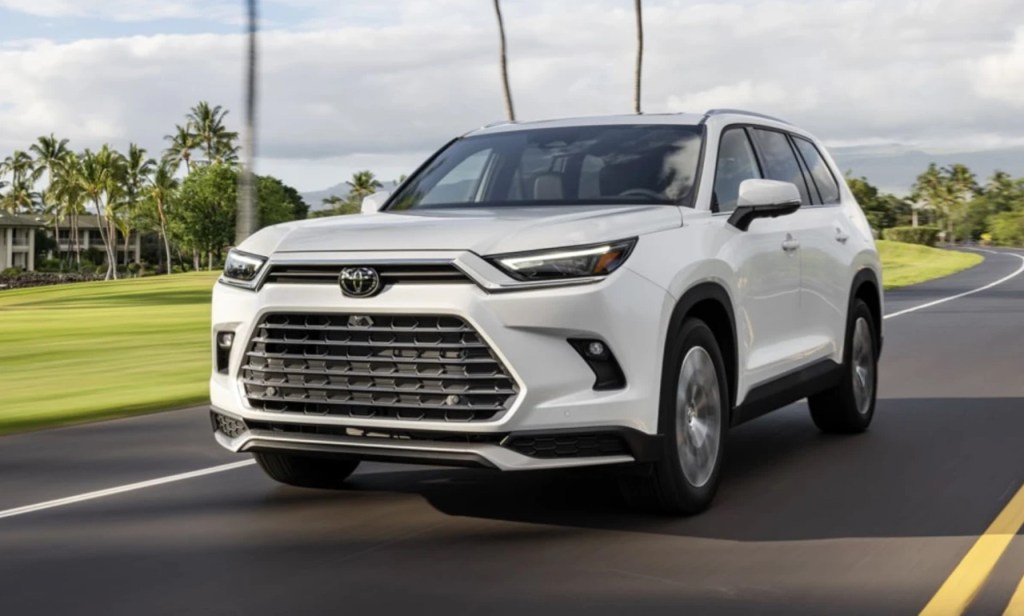 A white 2024 Toyota Grand Highlander driving on the pavement