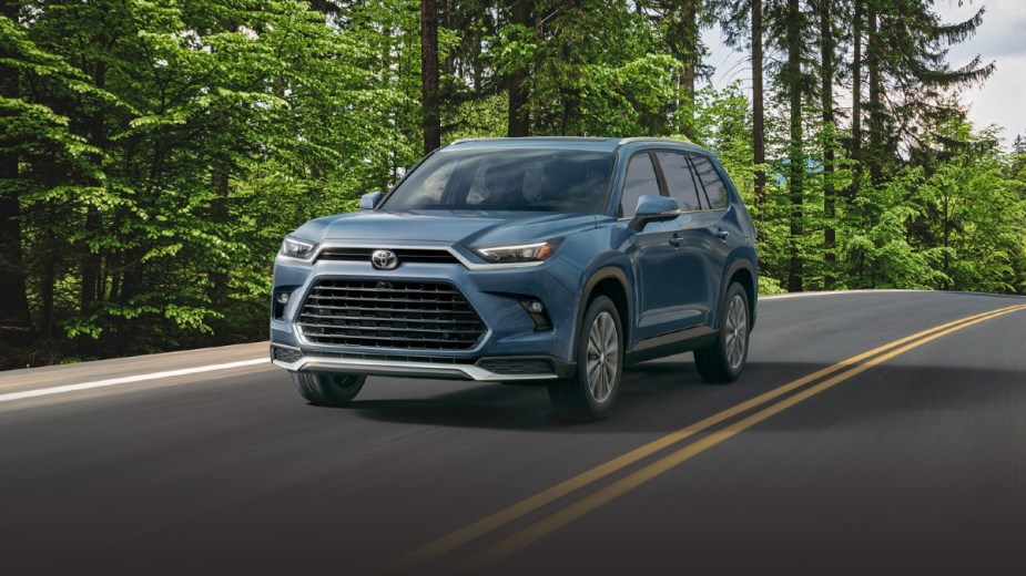 2024 Toyota Grand Highlander driving down a row with trees on the side