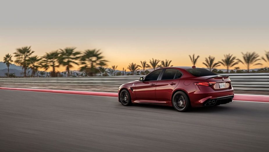 A red 2022 Alfa Romeo Giulia Quadrifoglio, like a Dodge Charger Hellcat, uses copious horsepower to attack a test track at sunset. 