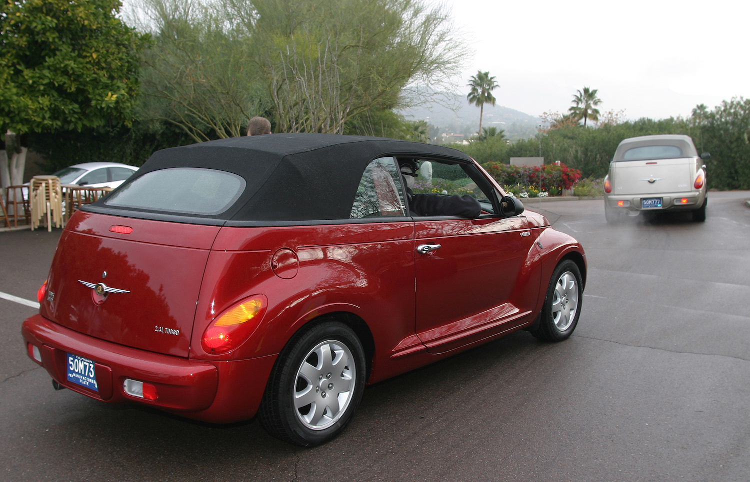 Two early convertible PT Cruisers driving away from the camera for a press event.