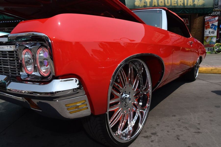 A donk car Chevy Impala, like the Caprice, shows off its high riser big wheels and bright color.