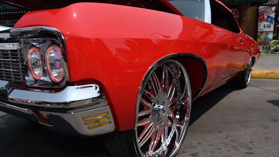 A donk car Chevy Impala, like the Caprice, shows off its high riser big wheels and bright color.