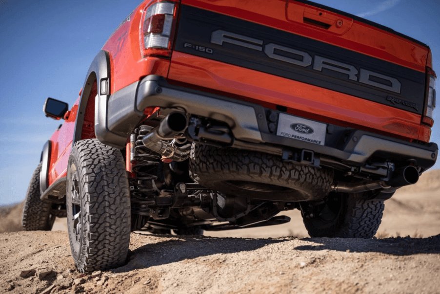A rear and undercarriage shot of a 2023 Ford F-150 Raptor full-size pickup truck model driving over dirt hills