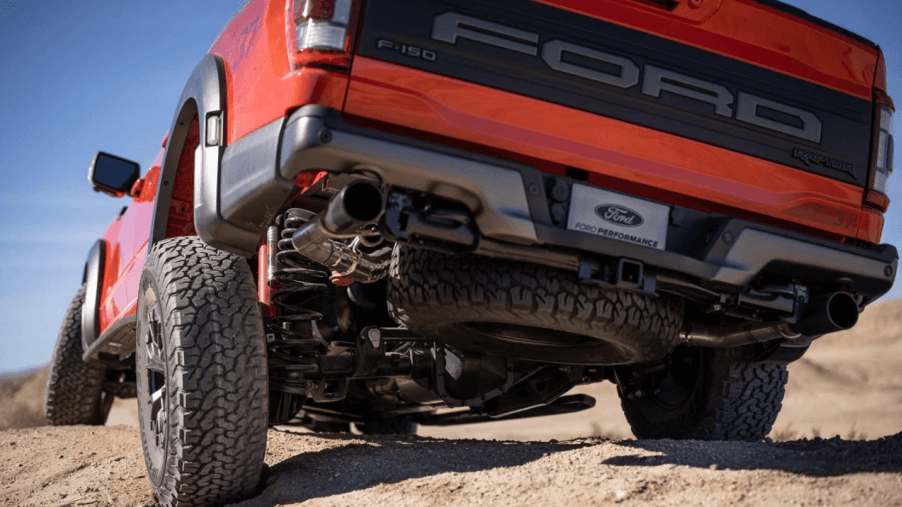 A rear and undercarriage shot of a 2023 Ford F-150 Raptor full-size pickup truck model driving over dirt hills