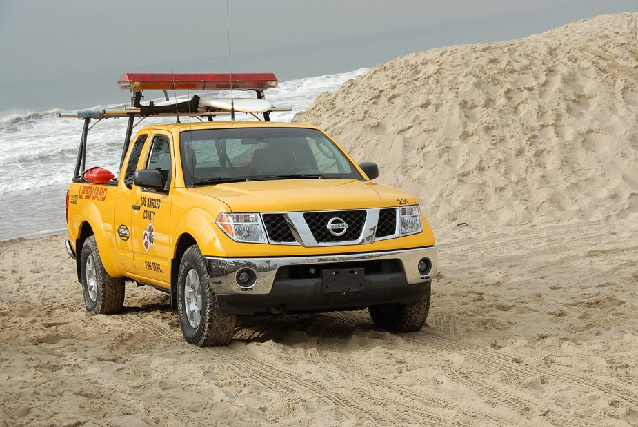 A yellow Nissan Frontier drives on a beach as a mid-size truck.