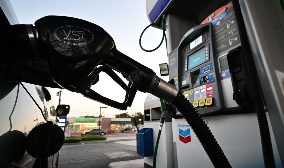 A nozzle pumps gasoline into a vehicle at a gas station
