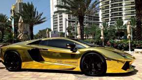 Gold-plated Lamborghini Gallardo supercar parked in front of a high-rise and palm trees in Florida.