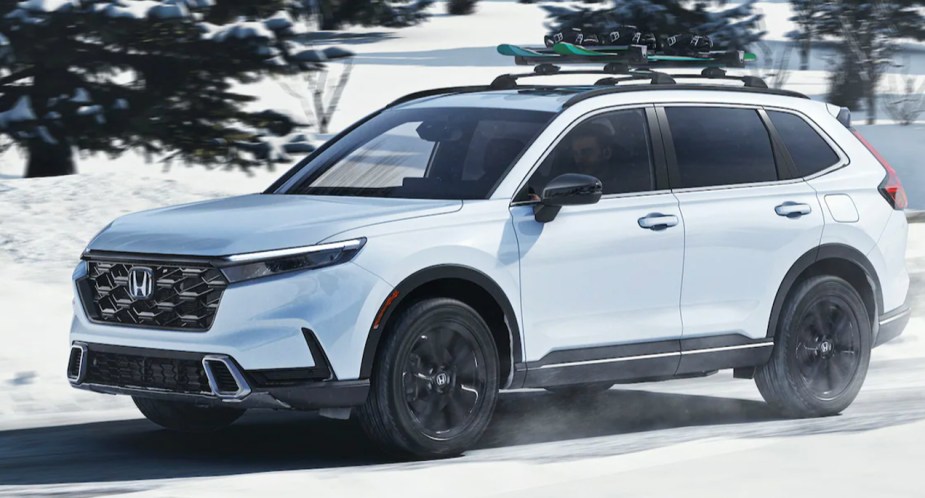 A white 2023 Honda CR-V small SUV is driving in the snow. 