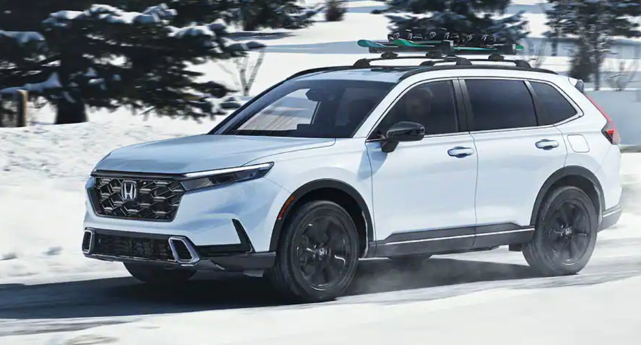 A white 2023 Honda CR-V small SUV is driving in the snow. 
