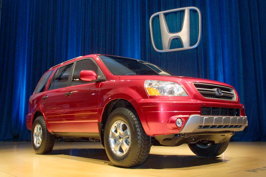 A used red Honda Pilot sits on a stage at an auto show. 
