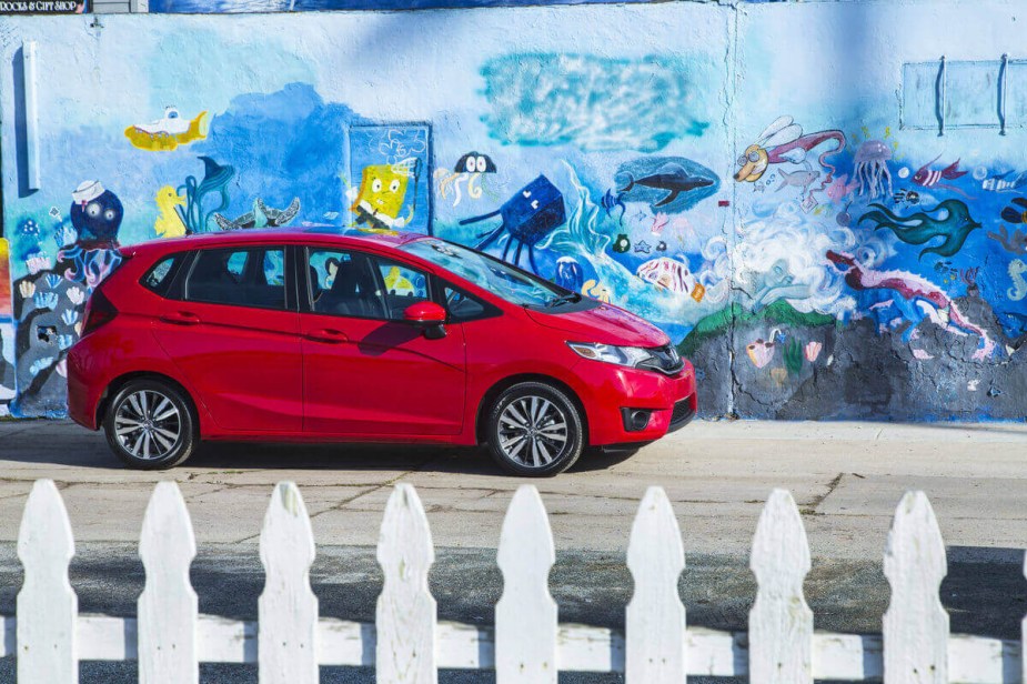 A 2016 Honda Fit shows off its profile against a graffiti wall. 