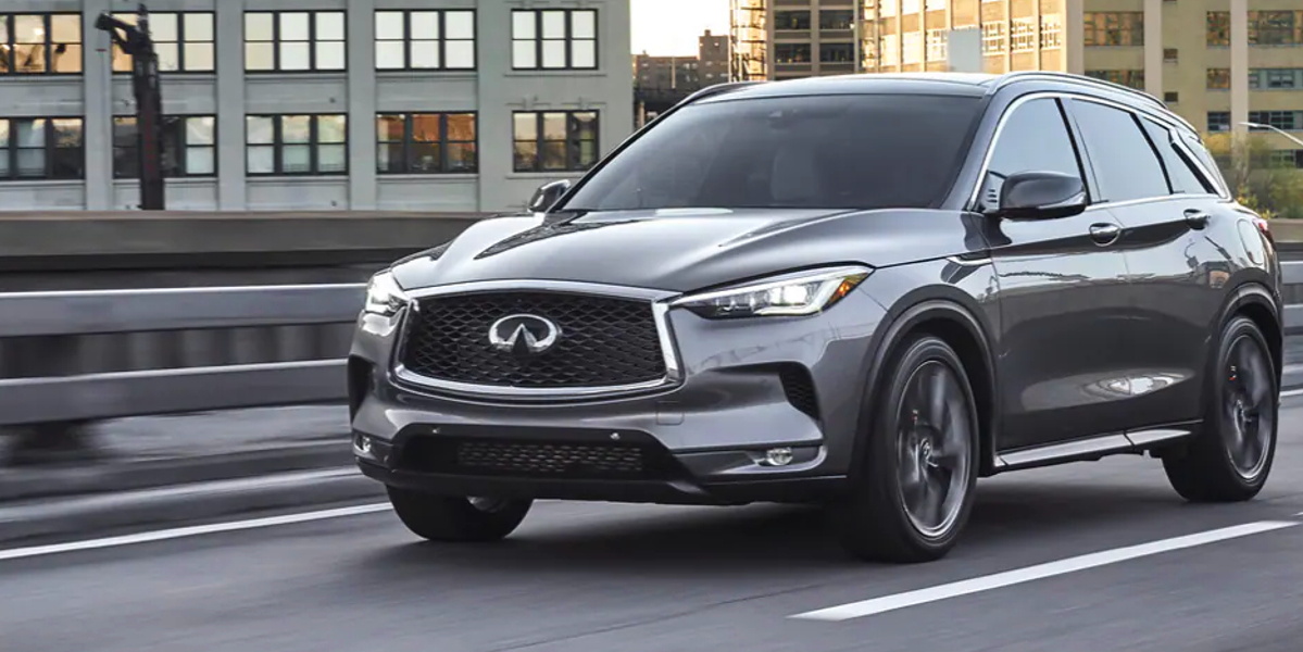 A gray 2023 Infiniti QX50 small luxury SUV is driving on the road.