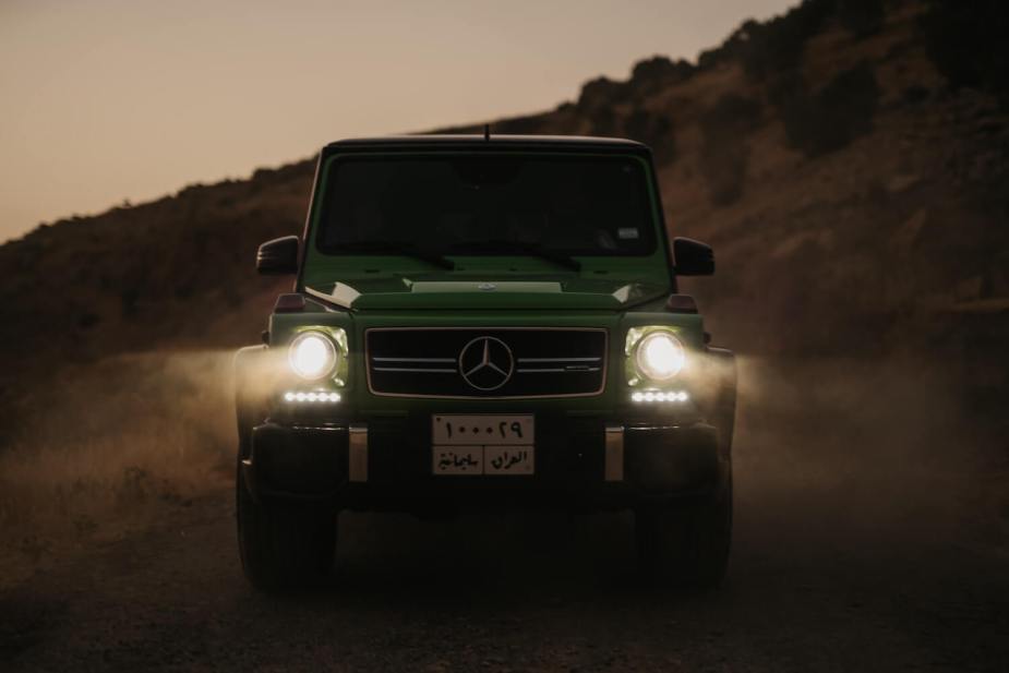 The boxy silhouette of a Mercedes G Wagon SUV with its headlights illuminated.